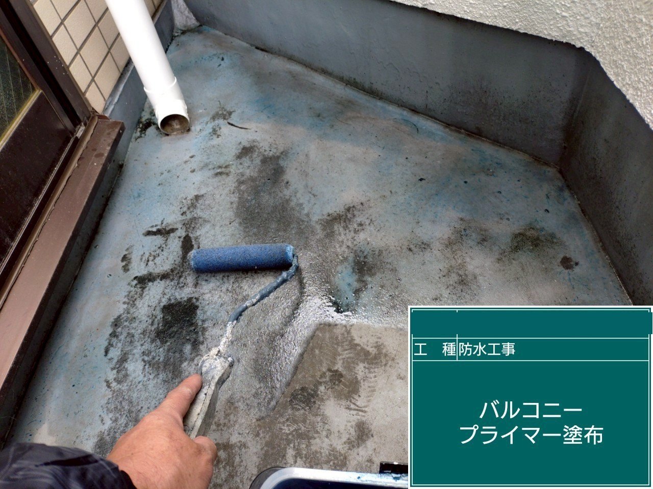 バルコニーの床にプライマーをローラーで塗っている様子