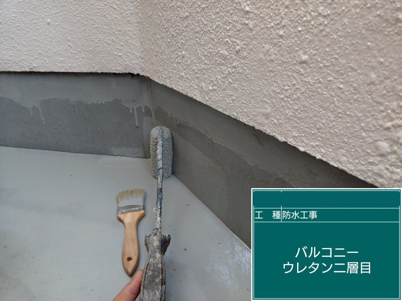 バルコニーの壁際の立ち上がりにウレタン防水の2層目を塗っている様子